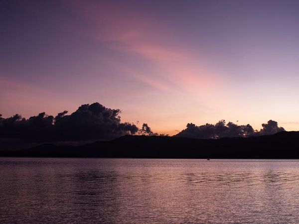 A serene landscape at dusk with soft pink clouds over calm water.